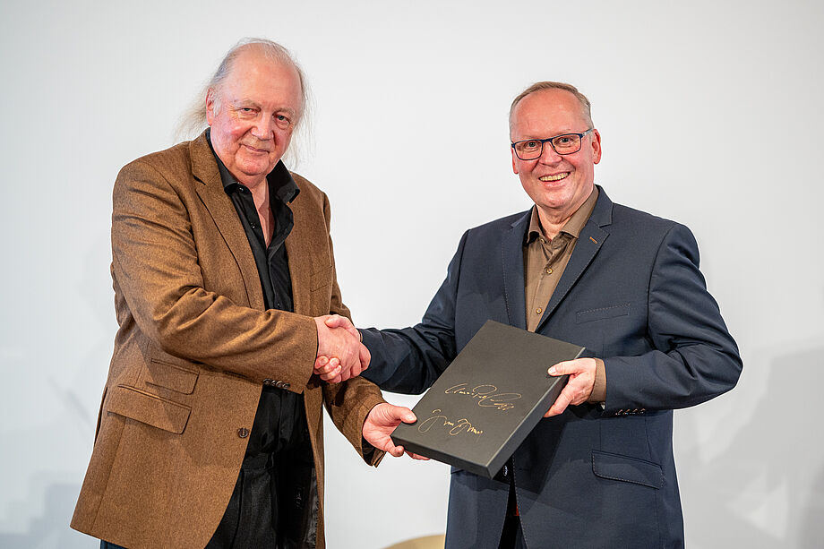 Jürgen Dollase überreicht Claus-Peter Lumpp ein Exemplar der Geschmacksdokumentation zum Lamm von der Älbler Wacholderheide. Foto: Crispin-Iven Mokry